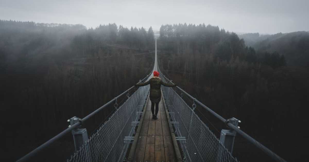 Person standing on a suspension bridge over a mountain valley. How do you overcome fear.